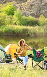 Young woman with hot drink resting outdoors. Camping vacation