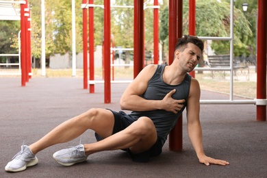 Young man having heart attack on sports ground