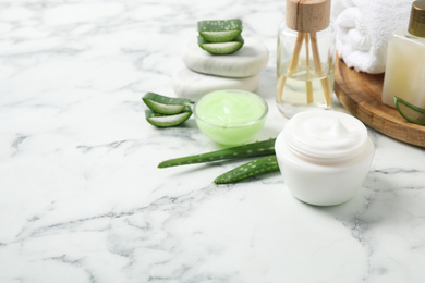 Photo of Different cosmetic products and aloe on white marble table, space for text