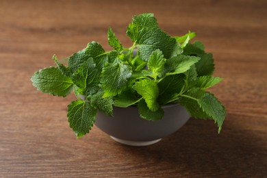 Fresh lemon balm in bowl on wooden table