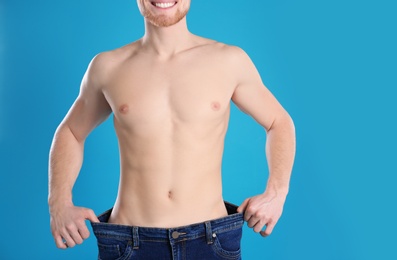Photo of Young man in oversized jeans on color background, closeup