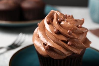 Delicious cupcake decorated with cream on plate, closeup view