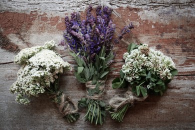 Photo of Bunches of beautiful dried flowers on wooden table, flat lay