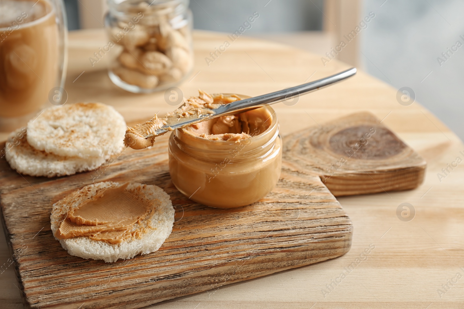 Photo of Jar of creamy peanut butter with bread on wooden board