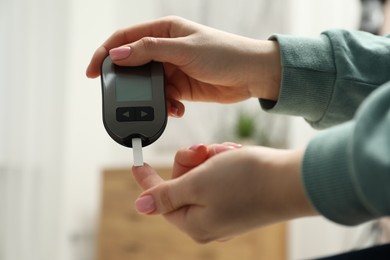 Diabetes. Woman checking blood sugar level with glucometer at home, closeup