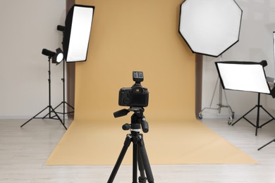 Photo of Camera on tripod and professional lighting equipment in modern photo studio