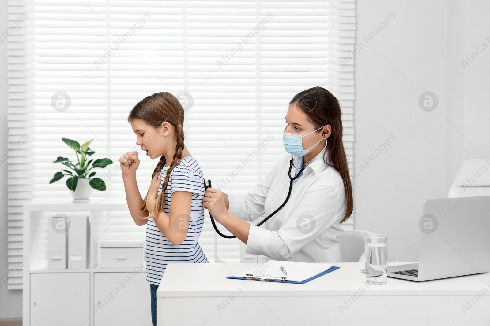 Photo of Doctor examining coughing girl in hospital. Cold symptoms