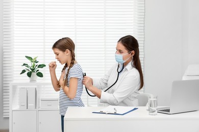 Doctor examining coughing girl in hospital. Cold symptoms