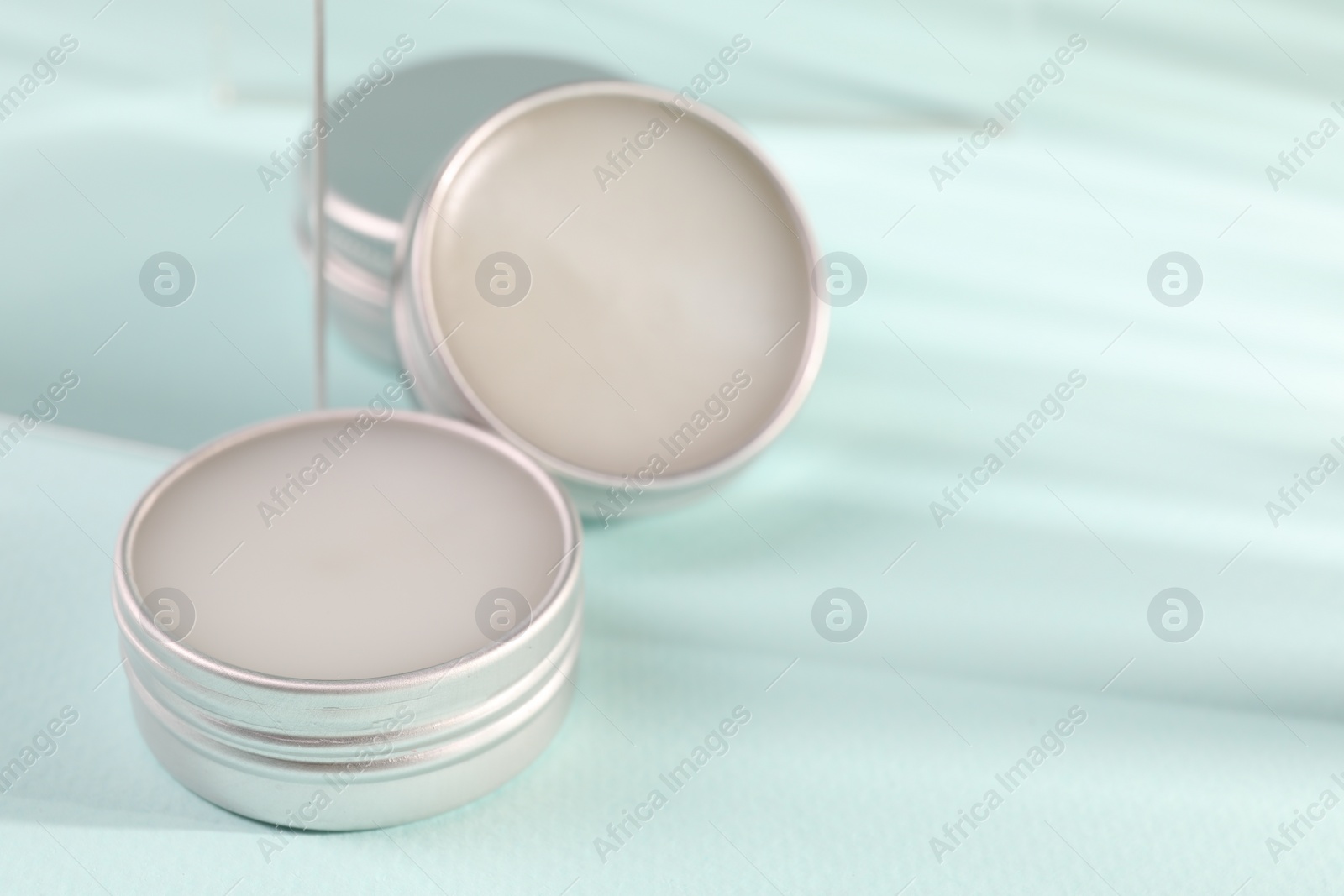 Photo of Lip balms on light blue background, space for text