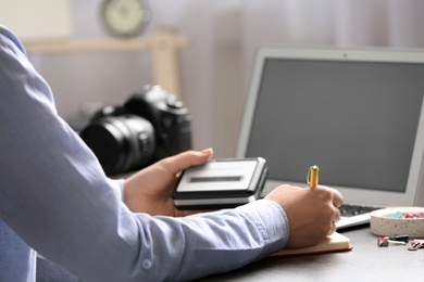 Journalist with voice recorder working at table in office, closeup