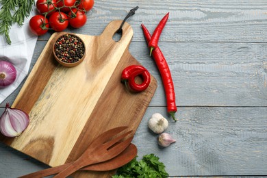 Photo of Cutting board and vegetables on grey wooden table, flat lay with space for text. Cooking utensils