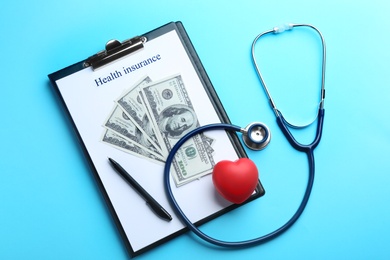 Flat lay composition with medical insurance form, money, heart and stethoscope on blue background