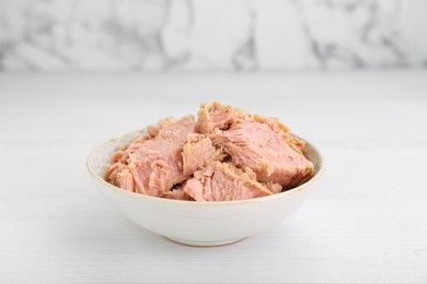 Photo of Bowl with canned tuna on white table, closeup