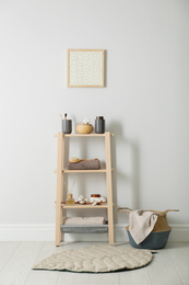 Wooden shelving unit with toiletries near white wall indoors. Bathroom interior element