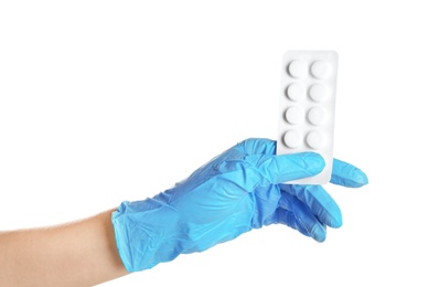 Doctor in medical glove holding pills on white background