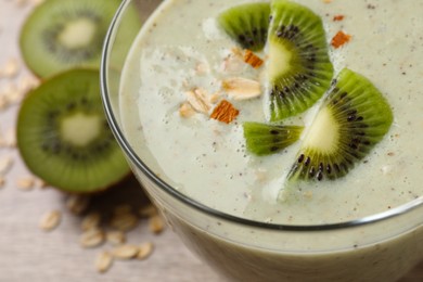 Photo of Glass of tasty kiwi smoothie with oatmeal on table, closeup