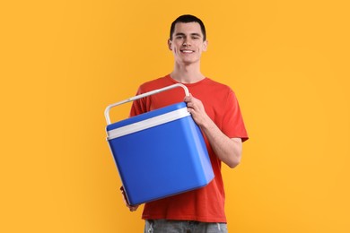 Man with blue cool box on orange background