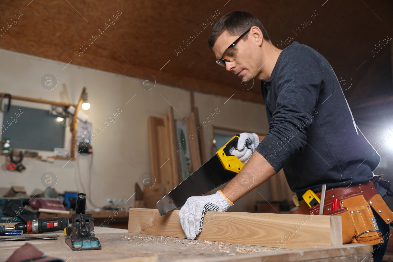 Photo of Professional carpenter sawing wooden plank at workbench