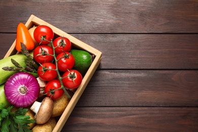 Fresh vegetables in crate on wooden table, top view. Space for text