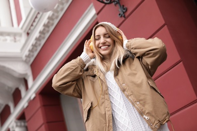 Young woman with headphones listening to music outdoors. Space for text