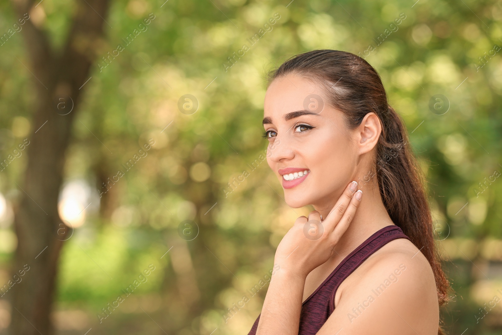 Photo of Young woman checking pulse outdoors on sunny day