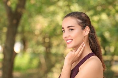 Young woman checking pulse outdoors on sunny day