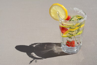 Photo of Delicious refreshing lemonade with raspberries on light gray rattan surface. Space for text