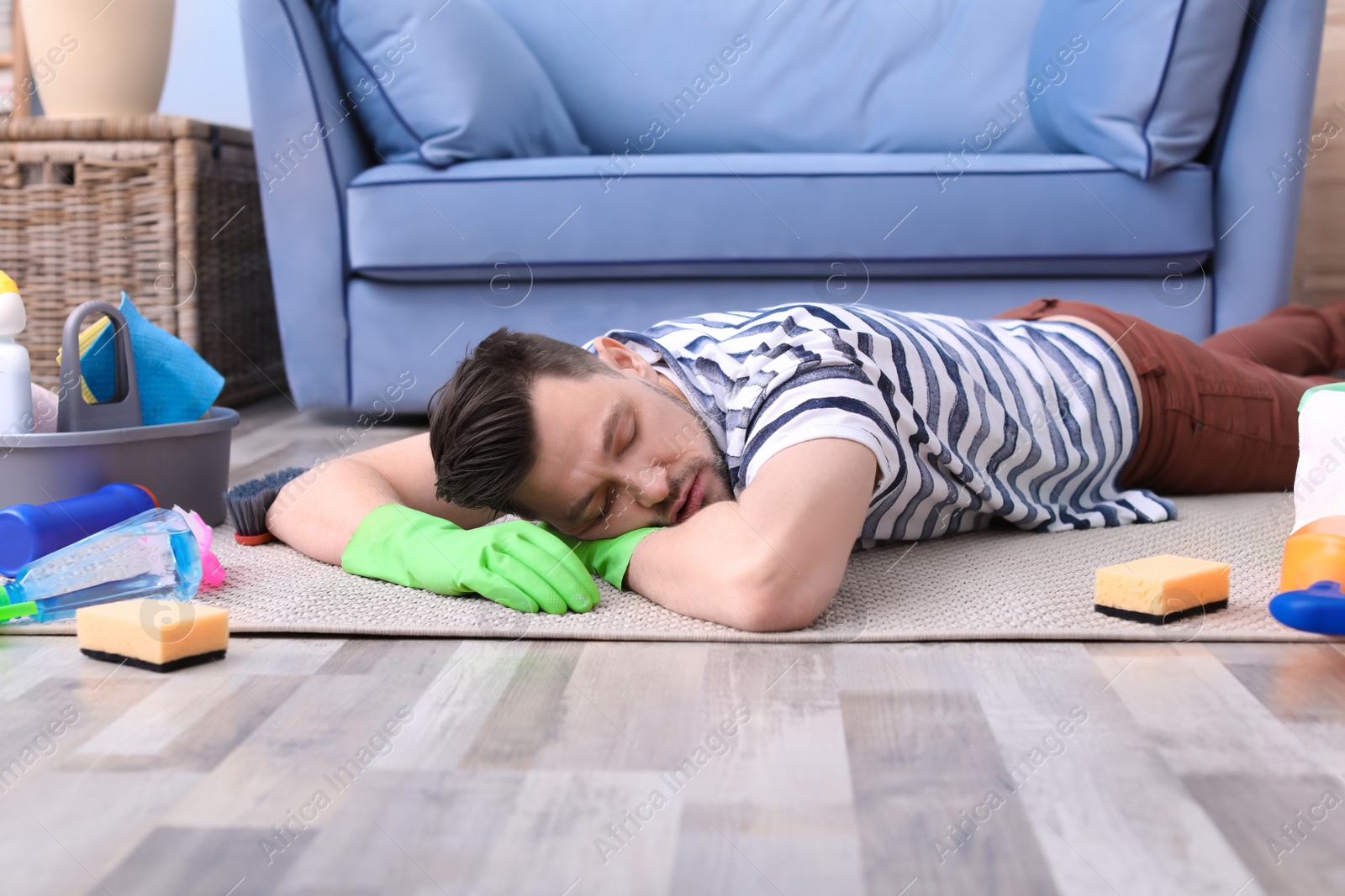 Photo of Tired man sleeping on floor after cleaning carpet at home