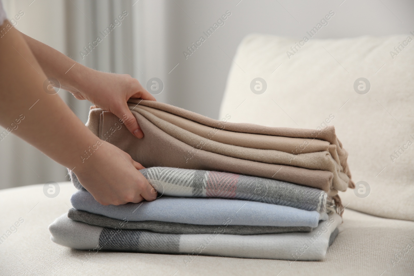 Photo of Woman with folded cashmere clothes indoors, closeup