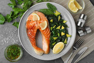 Photo of Tasty salmon with spinach served on grey table, flat lay