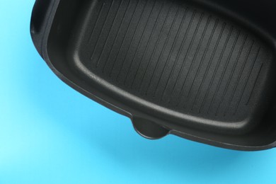 Photo of Black pot on light blue background, top view. Space for text