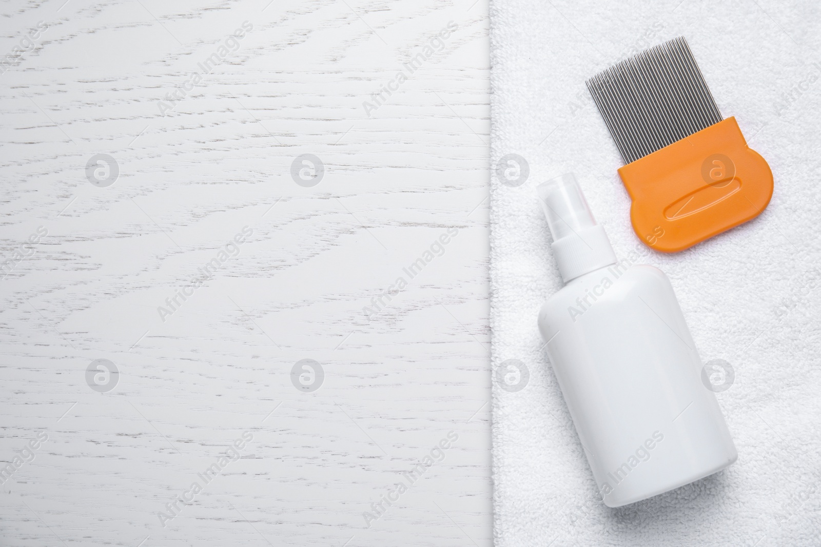 Photo of Spray, metal comb and towel for anti lice treatment on white wooden background, flat lay. Space for text