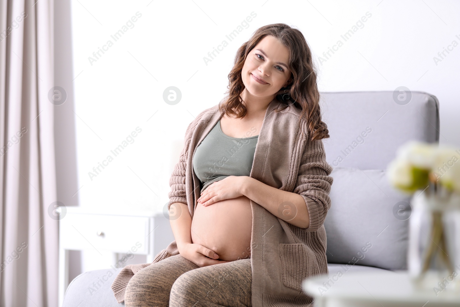 Photo of Young pregnant woman in casual clothes at home