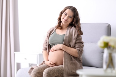 Photo of Young pregnant woman in casual clothes at home