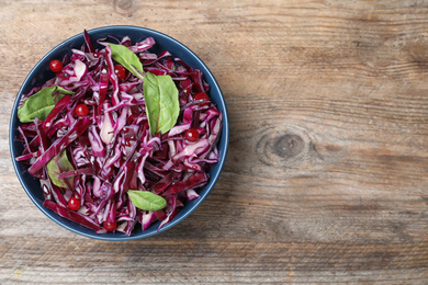 Photo of Fresh red cabbage salad served on wooden table, top view. Space for text