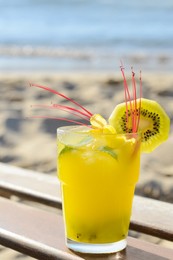 Photo of Glass of refreshing drink with kiwi and mint near sea, closeup