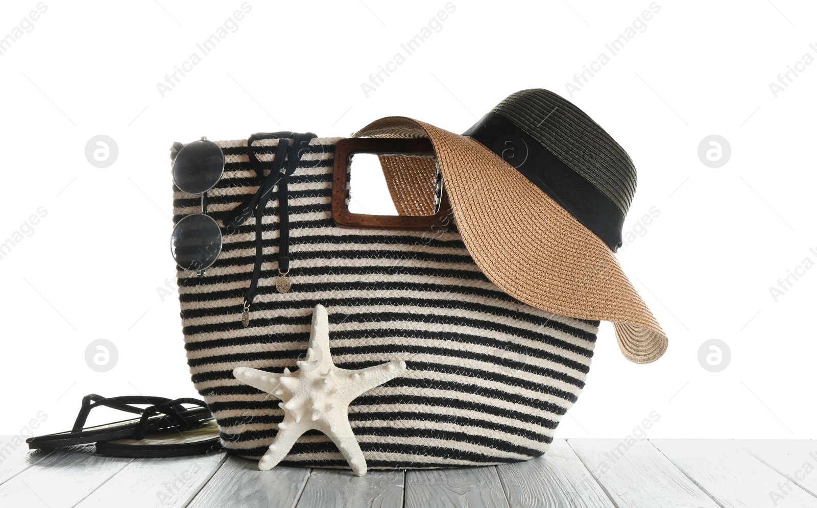 Photo of Set of beach accessories on wooden table, white background