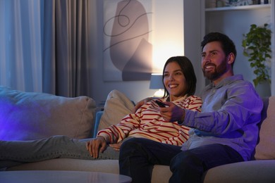 Photo of Happy couple watching TV on sofa at home, space for text