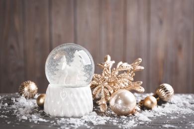 Photo of Beautiful snow globe and Christmas decor on grey wooden table