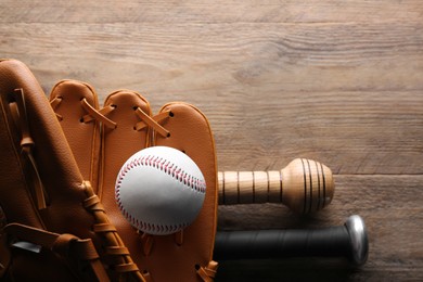 Photo of Baseball glove, bats and ball on wooden table, flat lay. Space for text