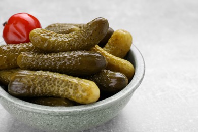 Photo of Bowl of pickled cucumbers and pepper on light grey table, closeup