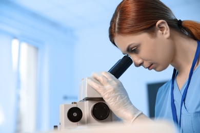 Female scientist using microscope in chemistry laboratory, space for text