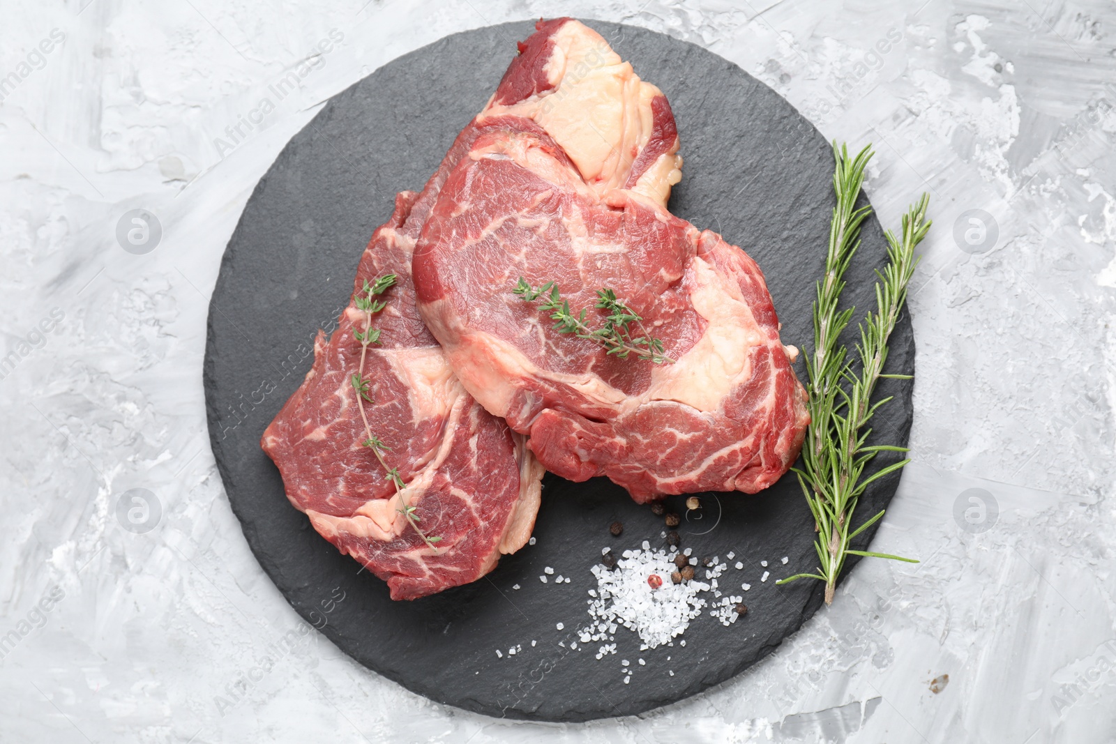 Photo of Fresh raw beef cut with different spices on light grey textured table, top view