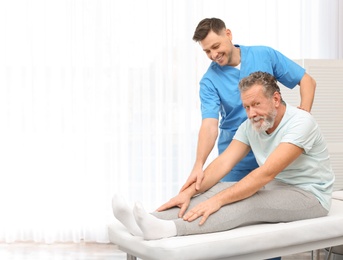 Photo of Physiotherapist working with patient in clinic, space for text. Rehabilitation therapy