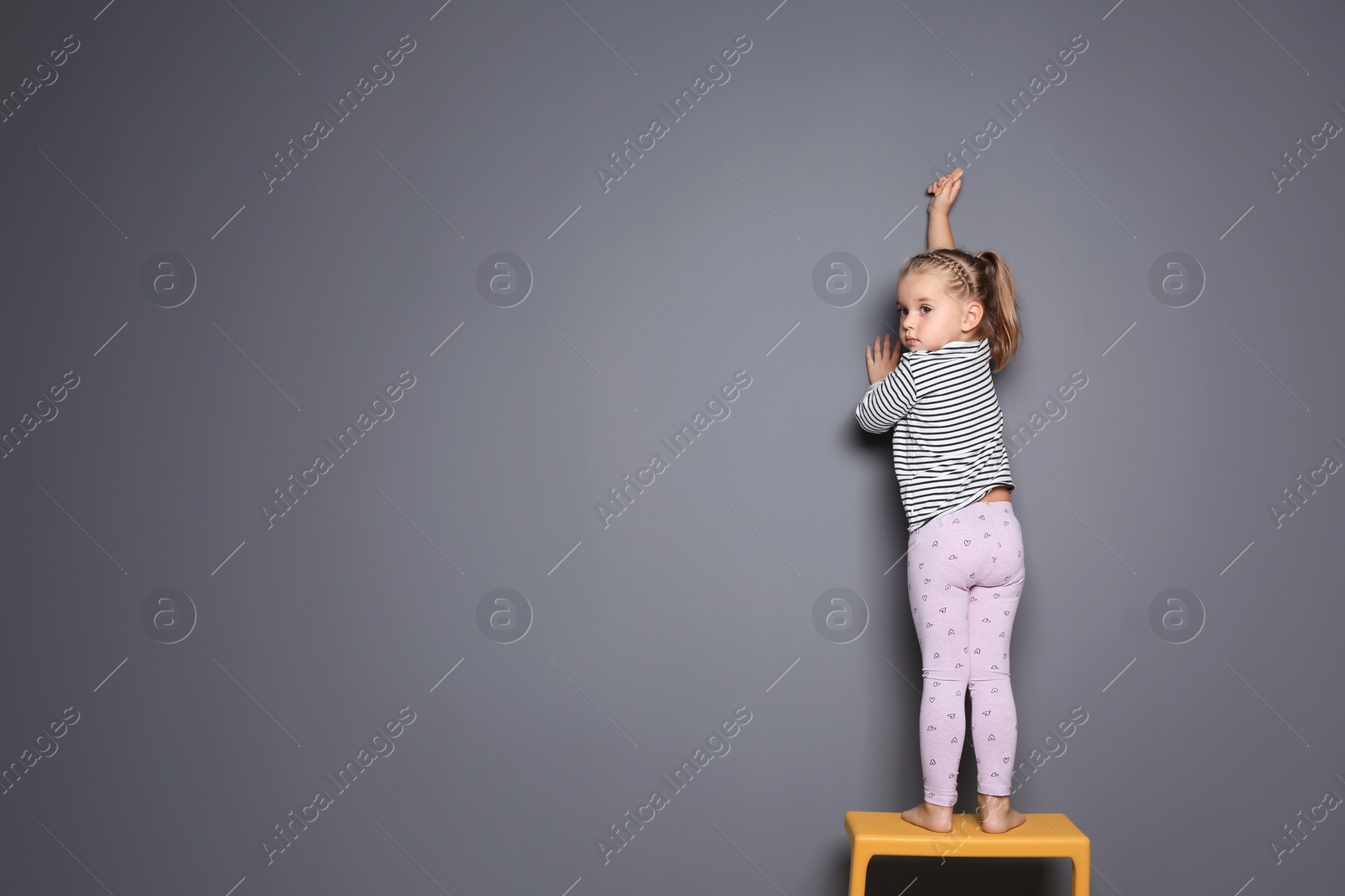 Photo of Little child drawing with colorful chalk on gray background. Space for design