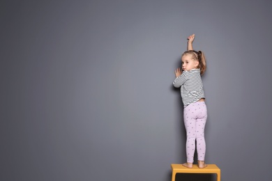 Little child drawing with colorful chalk on gray background. Space for design