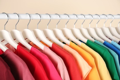 Photo of Many t-shirts hanging in order of rainbow colors, closeup