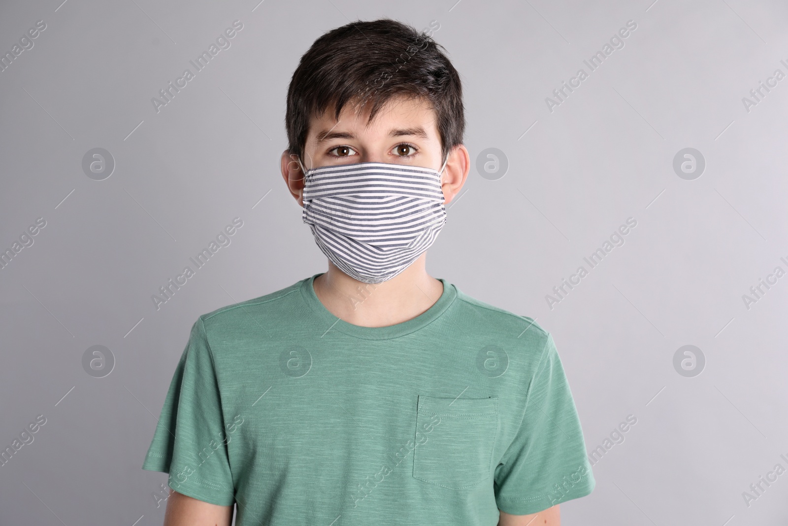 Photo of Boy wearing protective mask on light grey background. Child safety