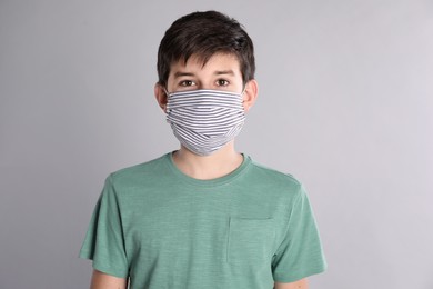 Boy wearing protective mask on light grey background. Child safety