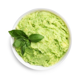 Bowl of tasty avocado sauce with basil on white background, top view